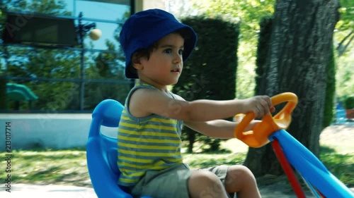 Little cute boy having fun driving a pedal car in the park. 4K photo