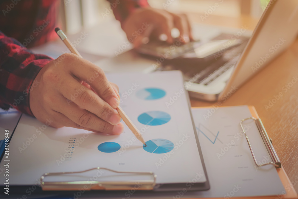 Working process startup. Businessman working at the wood table with new finance project. Modern notebook on table. Pen holding hand Working process startup. Businessman working at the wood table with new finance project. Modern notebook on table. Pen holding hand