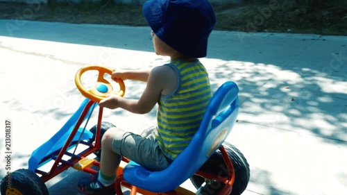 Little cute boy having fun driving a pedal car in the park. 4K photo