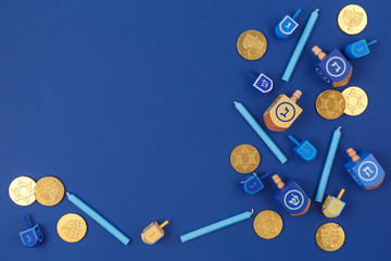 Dark blue background with multicolor dreidels and chocolate coins. Hanukkah and judaic holiday concept.