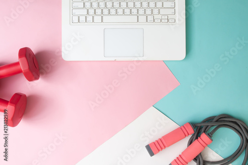 Creative flat lay laptop computer and fitness equipments on pastel color background, Healthy lifestyle concept