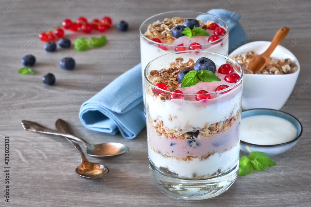 Yogurt with muesli and berries, healthy dessert on neutral wood Yogurt with muesli and berries, healthy dessert on neutral wood
