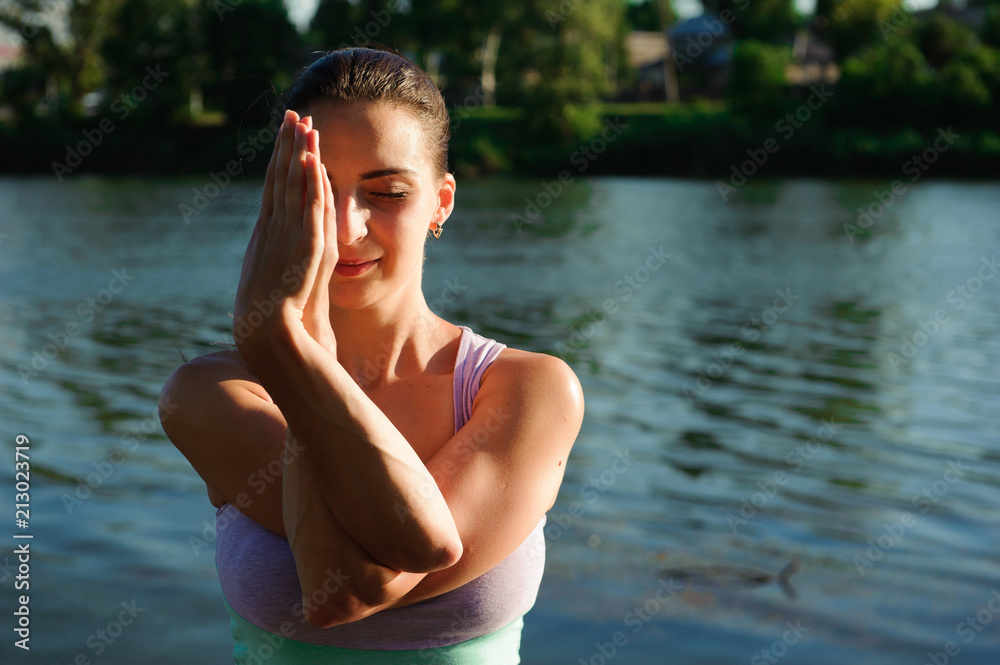 Young healthy woman practicing yoga on the bridge in the nature
