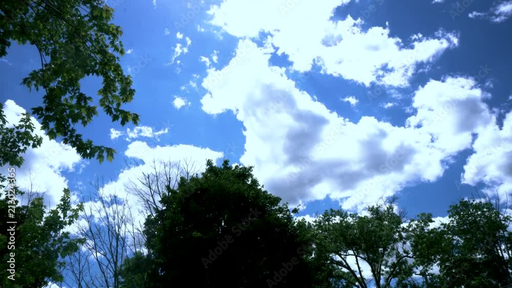 White clouds float across a blue summer sky while the sun shines through. White clouds float across a blue summer sky while the sun shines through.