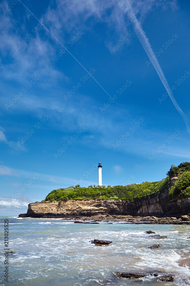 Biarritz, France. Sand beach Miramar Plage overlooking the white lighthouse - Phare de Biarritz on the Pointe Saint-Martin.  Bay of Biscay, Atlantic coast, Basque country. Sunny summer day