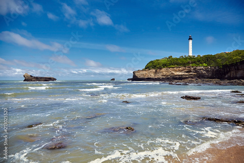 Biarritz, France. Sand beach Miramar Plage overlooking the white lighthouse - Phare de Biarritz on the Pointe Saint-Martin. Bay of Biscay, Atlantic coast, Basque country. Sunny summer day