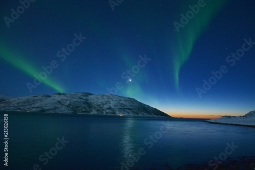 The northern lights  Aurora Borealis  over Seljelvnes  Troms by the sea and the snowy mountains