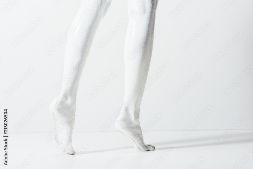 cropped image of girl with legs painted with white paint walking on white floor cropped image of girl with legs painted with white paint walking on white floor
