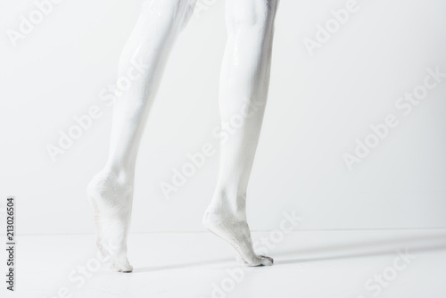 cropped image of girl with legs painted with white paint walking on white floor