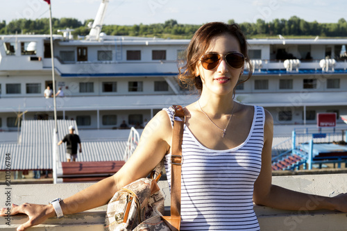 Beautiful girl with bag on shoulder  background of ship