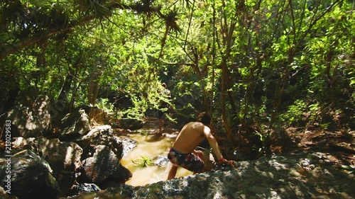 SLOWMO, Young man explores a tropical jungle, ducking under branches and walking through a stream at Christoffelpark, Curacao. photo