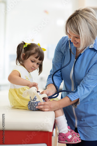 Doctor examining toy and little girl using stethoscope