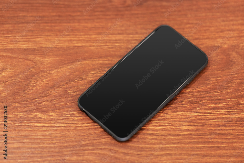 Mobile phone with blank screen on wooden table background.