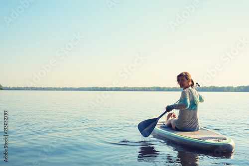 Smiling female relaxing on a SUP board and enjoying life