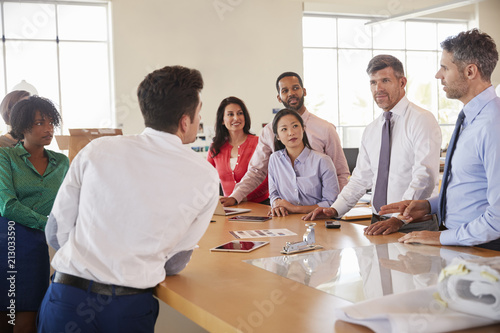 Business team stand at a meeting around a table in an office