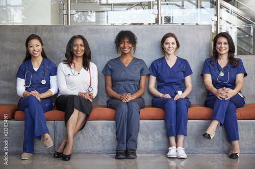 Female healthcare workers sitting in a hospital, full length
