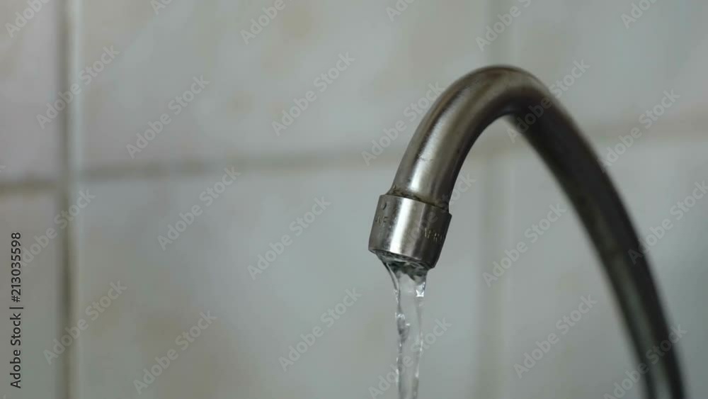 Water under weak pressure flows from a water tap Water under weak pressure flows from a water tap