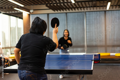 Girls is playing table tennis at the office.