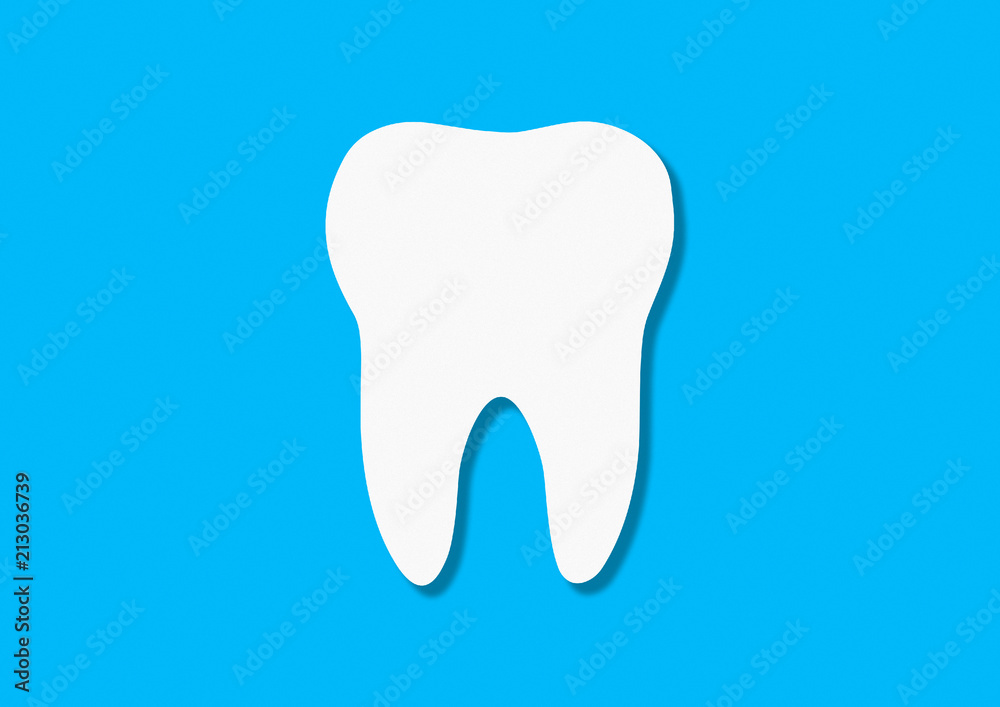 Healthy white tooth cut from colored paper on a blue background. Handmade. The concept of dental care and dentistry. Flat lay, top view Healthy white tooth cut from colored paper on a blue background. Handmade. The concept of dental care and dentistry. Flat lay, top view