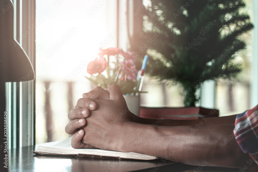 Close up hands man praying on holy Bible at home. Close up hands man praying on holy Bible at home.