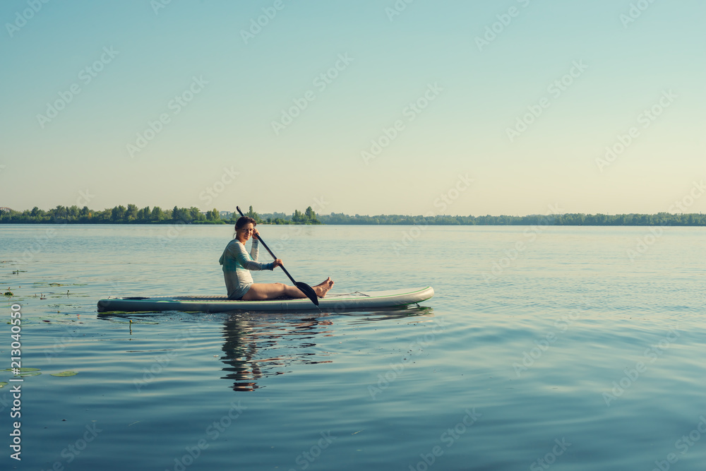 Smiling female relaxing on a SUP board and enjoying life