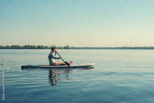 Smiling female relaxing on a SUP board and enjoying life