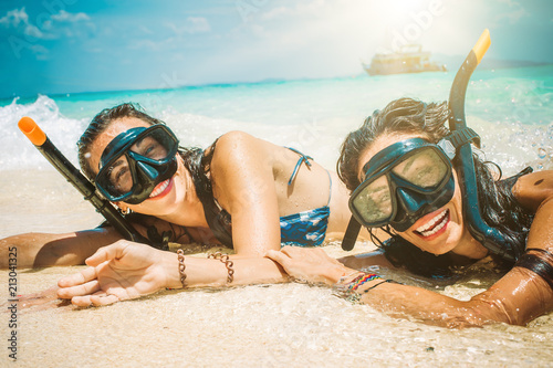 Two happy girlfriends with snorkeling mask enjoying on the beach photo