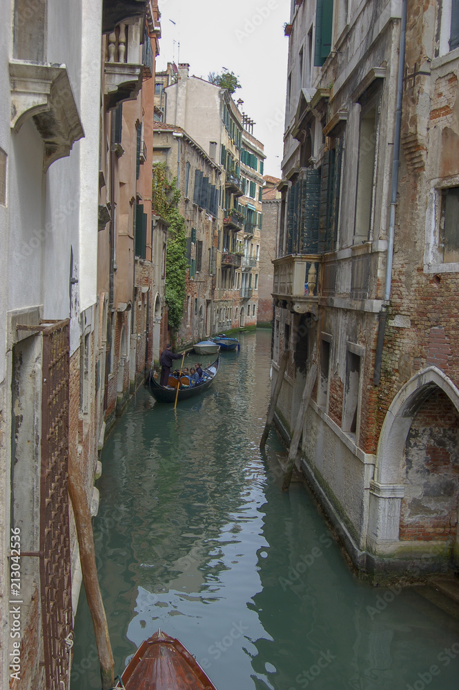Classic view of a narrow back cana with gondola and leaning buildings, Venice, Italty