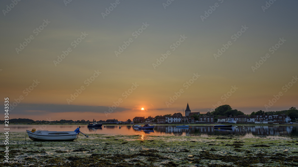 Summer sunset over Bosham Harbour and village with the church spire of Holy Trinity Church, West Sussex, UK