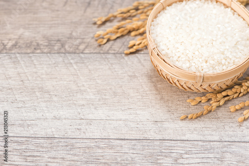 Close up raw rice and unmilled rice in traditions bamboo basket on wooden background, copy space(text space), blank for text