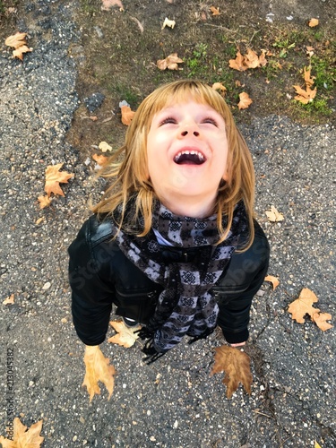 Boy with gold hair, playing with autumn lefs outside photo