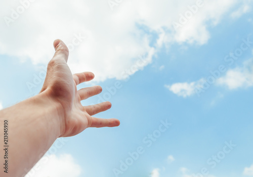 the human hand stretches to the blue sky