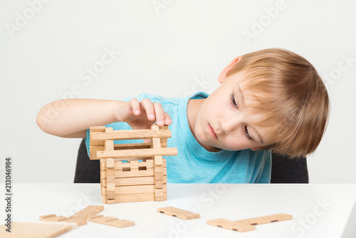 Little boy building house his dream. Kid building small house on table. Family and home concept. Smart kid create constructions with wooden blocks. Childhood and educational games concept.
