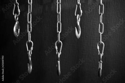 steel chains and hooks in from of black wall