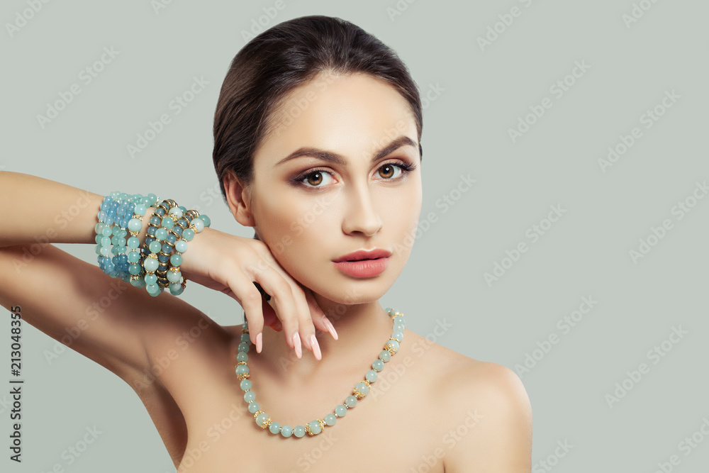 Attractive Young Woman with Makeup, Jewelry Necklace and Bracelet on Background with Copy space