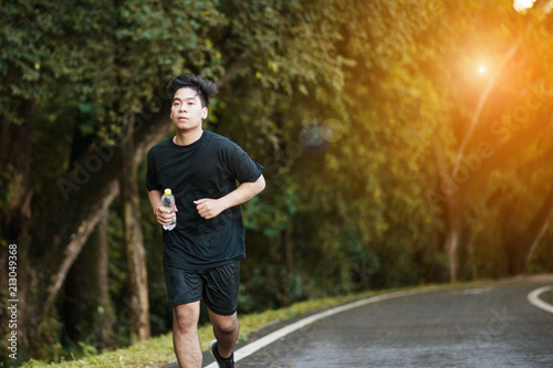 Active healthy runner jogging outdoor. Dinking water.