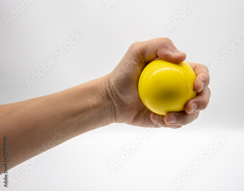 Hand holding yellow stress ball isolated on white