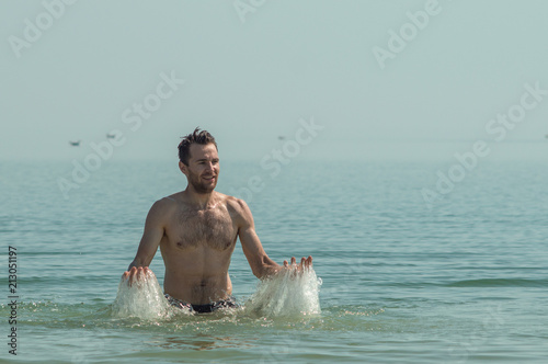 Man in the sea, sprinkles water, rest on the sea