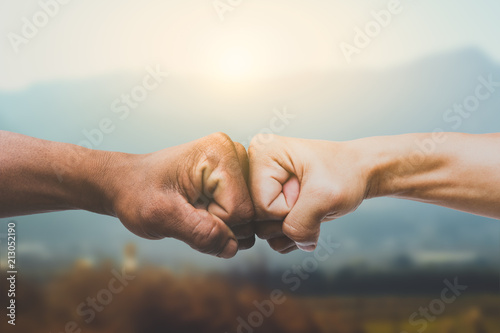 Man giving fist bump in sun rising nature background. power of teamwork concept. vintage tone photo