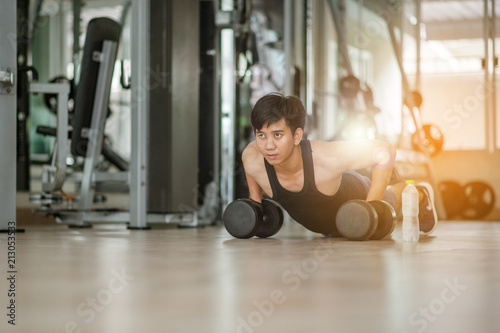Sport. Handsome man doing push ups exercise with one hand in fitness gym.Fitness instructor at the gym - Control your mind, conquer your body.Handsome muscular man is working out with dumbbells in gym