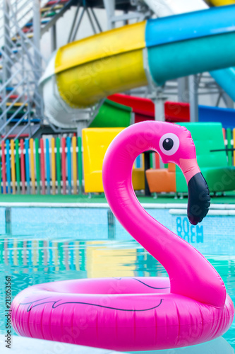 The inflatable circle in the form of a pink flamingo floats in the pool. Background aquapark