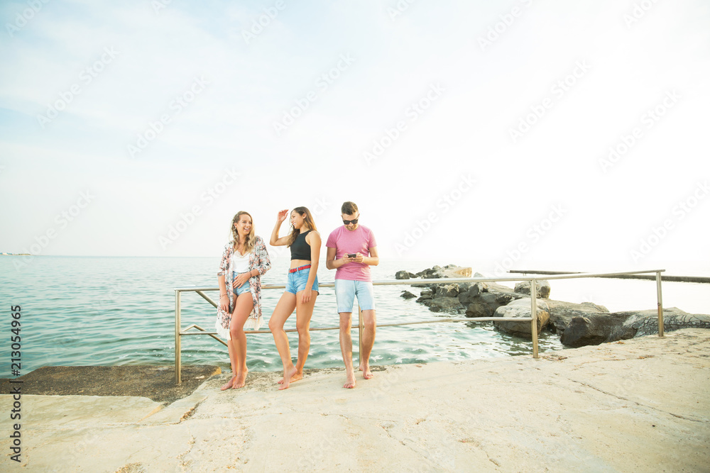 Three happy friends standing on a sea shore