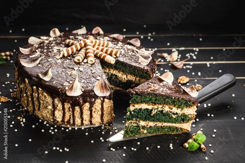 Sweet chocolate cake with tasty cream on the black wooden background