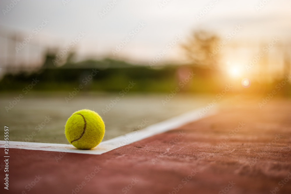 Tennis ball on hard court at sunset
