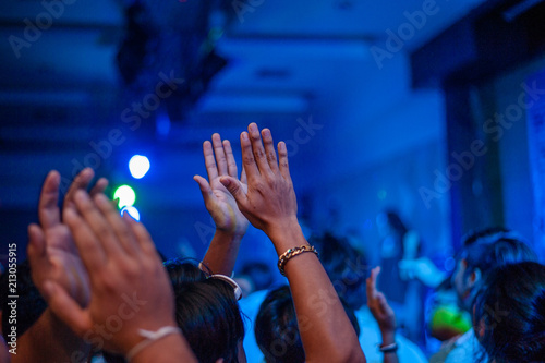 Grunge style photo of silhouette of people hands raised up on musical concert, enjoying music, dance club, active night life concept.