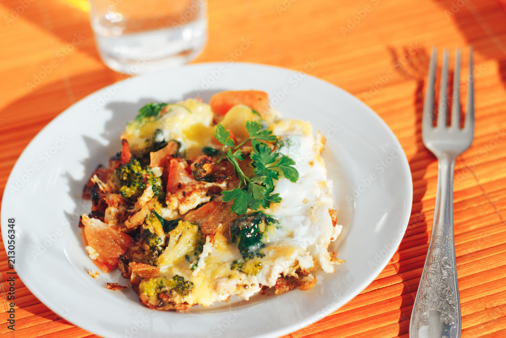 Scrambled eggs with tomatoes and greens on an orange background Scrambled eggs with tomatoes and greens on an orange background