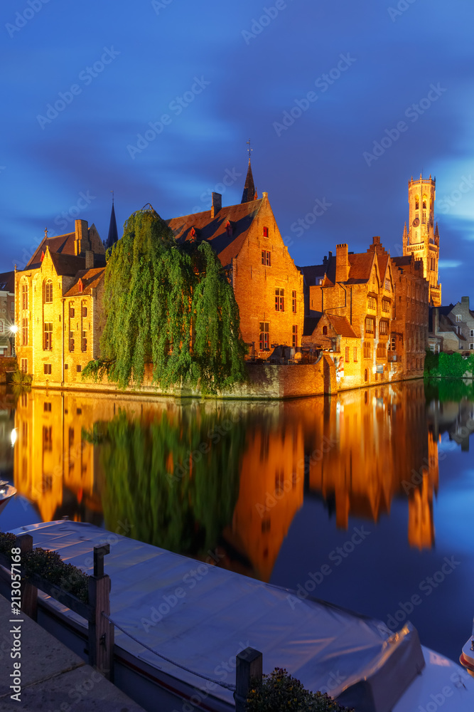 Scenic cityscape with a medieval fairytale town and tower Belfort from the quay Rosary, Rozenhoedkaai, at night in Bruges, Belgium