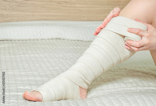 Woman applying elastic compression bandage after varicose surgery photo