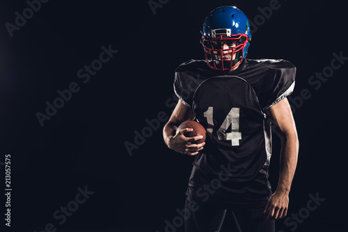 young american football player with ball looking at camera isolated on black