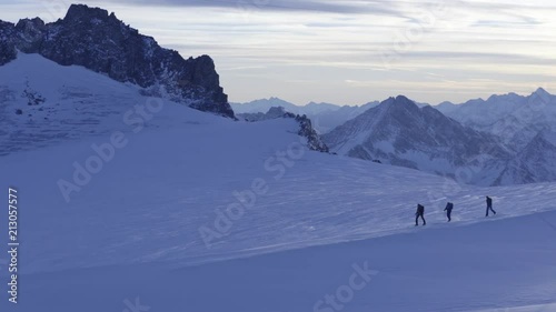Aerial shot of three people skiing the peak of the mountain. photo
